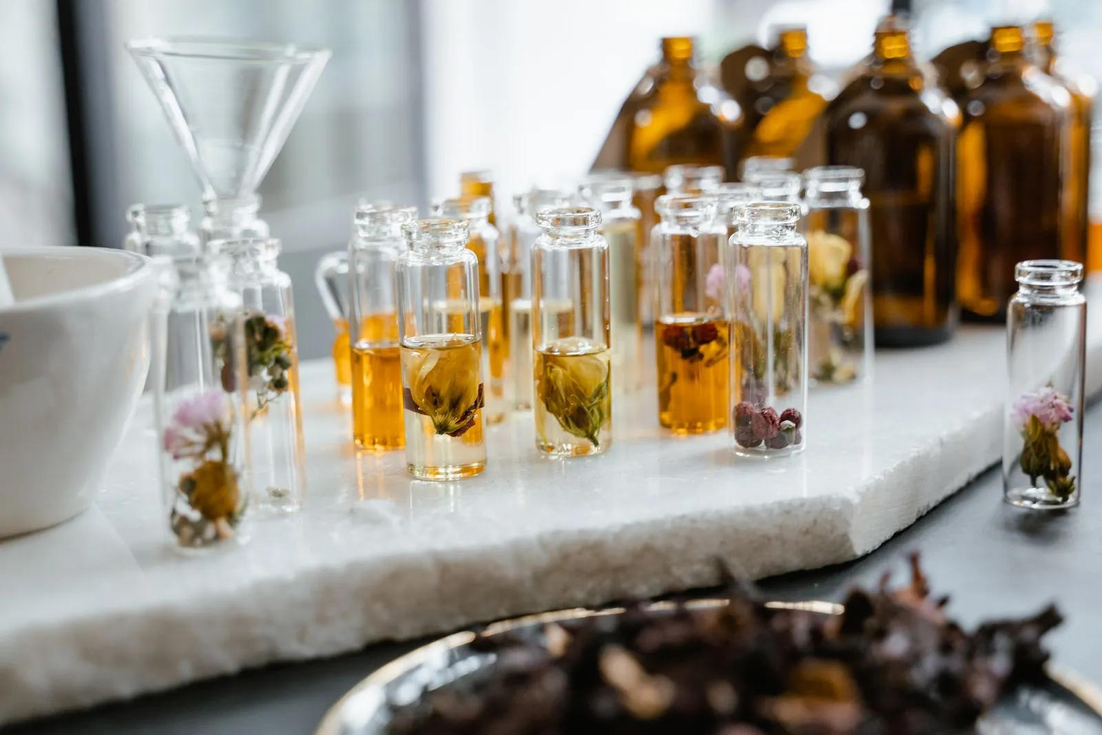 Close-up of various aromatic floral oils in glass bottles, showcasing their vibrant colors and natural ingredients.