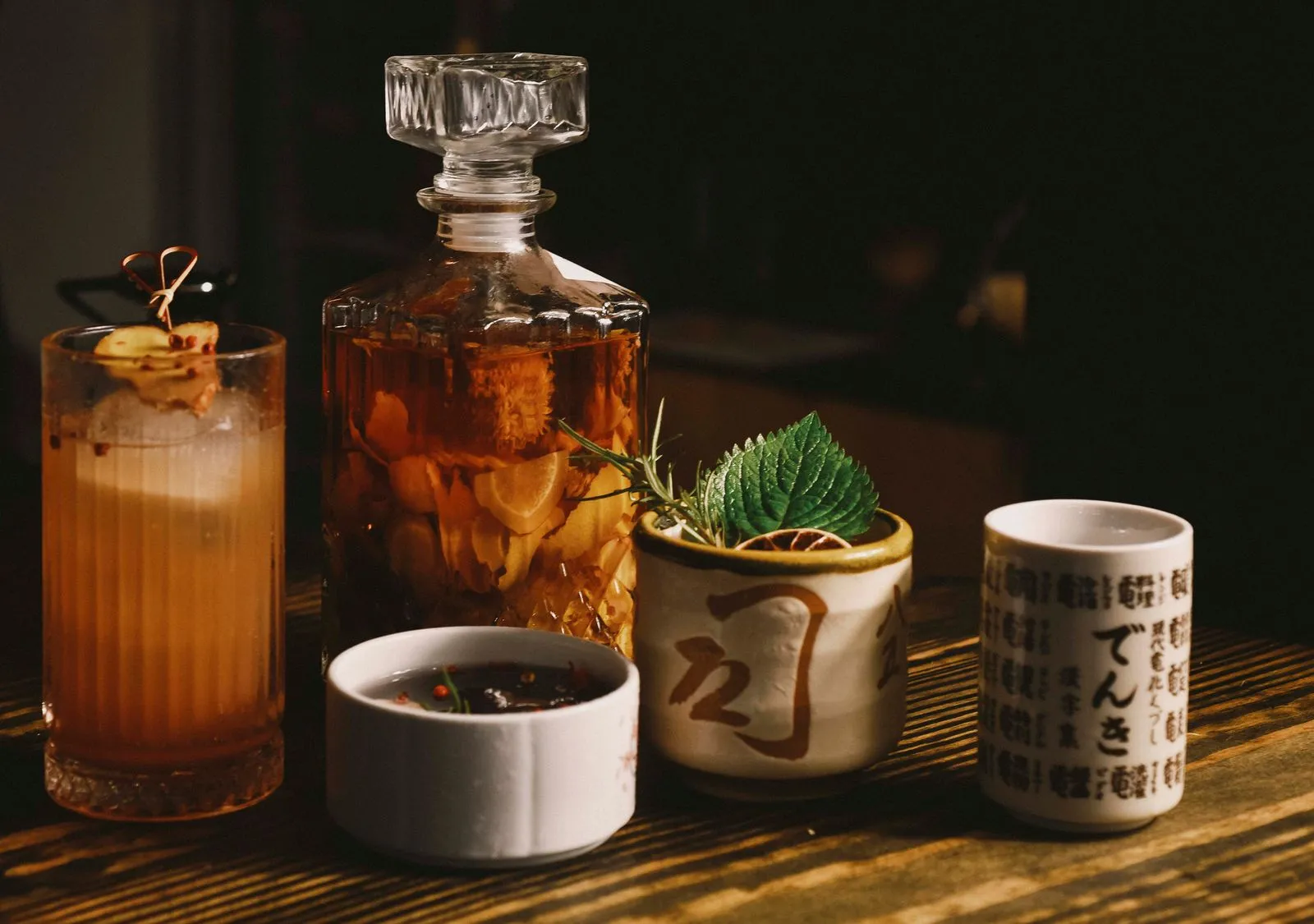 A creative still life of various drinks including a cocktail and herbal infusion, artistically arranged.